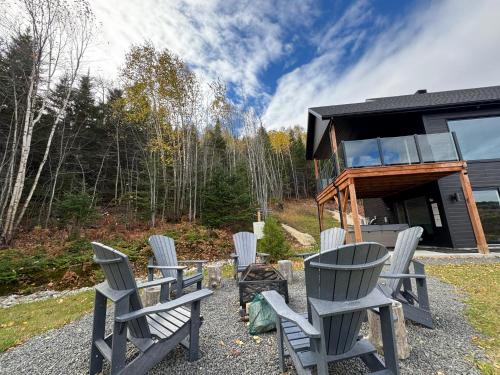 a group of chairs sitting in front of a house at Vertigo - Fleuve & Montagnes in Les Éboulements