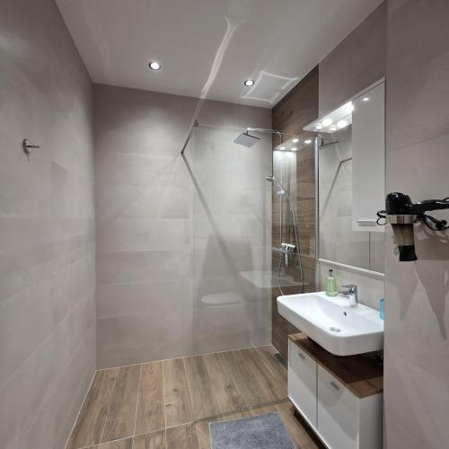 a bathroom with a white sink and a shower at Prestige Lux Andan - Apart hotel Horizont Jahorina in Jahorina