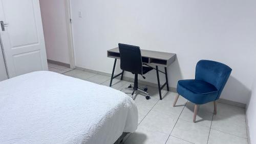 een slaapkamer met een bed, een bureau en 2 stoelen bij Croydon Vista Luxe in Kempton Park