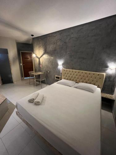 a bedroom with a large white bed and a stone wall at Eros Motel in Natal