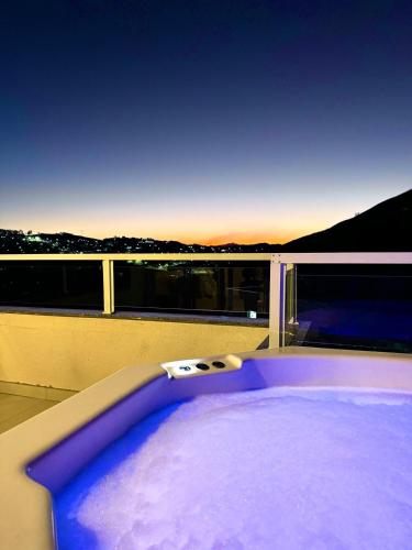 a jacuzzi tub on a balcony with the sunset at Charmoso Duplex com Jacuzzi in Poços de Caldas