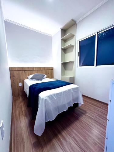 a bedroom with a large bed with a blue blanket at Charmoso Duplex com Jacuzzi in Poços de Caldas