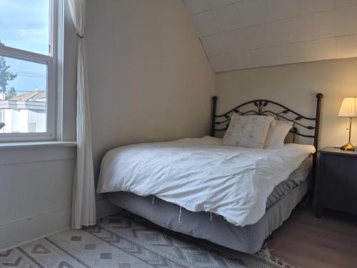 a bedroom with a bed with white sheets and a window at John's House in Vancouver West in Vancouver