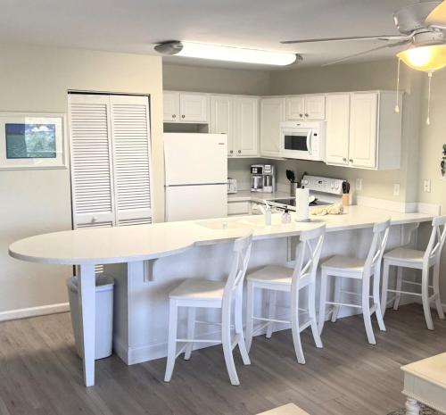 une cuisine avec des armoires blanches et une table et des chaises dans l'établissement Island Sands 103 Gulf front condo, à Fort Walton Beach