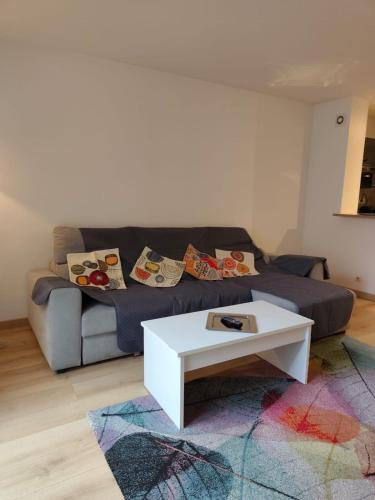 Charmant 3 pieces 2 chambres et parking في بونتولت-كومْبو: غرفة معيشة مع أريكة وطاولة قهوة بيضاء