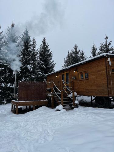 a log cabin in the snow with a couple of benches at Gypsy Hill & Spa in Międzylesie