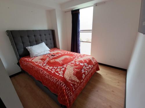 a bedroom with a bed with a red blanket and a window at Alojamiento Cómodo y Hermoso en apartamento 7 personas Carnavales in Pasto
