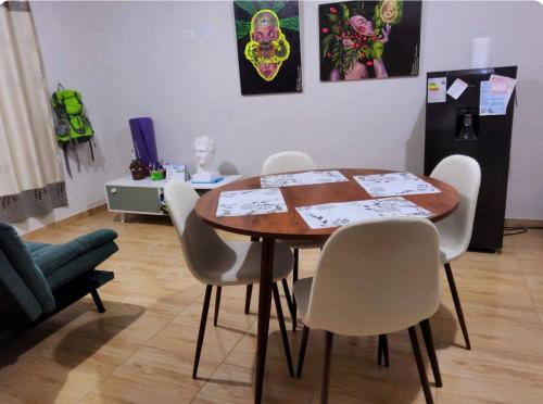 een eetkamer met een tafel en witte stoelen bij Casa hogareña Pequeña in Ica