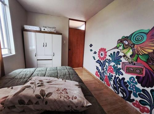 a bedroom with a bed with a painting on the wall at Casa hogareña Pequeña in Ica