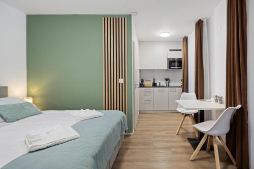 a bedroom with a bed and a table and a kitchen at STAYY Nº7 Suites & Studios -Self Check-in in Zürich