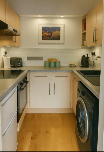 a kitchen with white cabinets and a washer and dryer at Bed on the Brae in Inverness