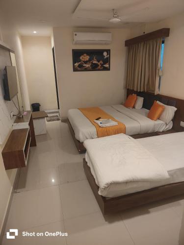 a hotel room with two beds and a television at Hotel VR Villa in Vadodara