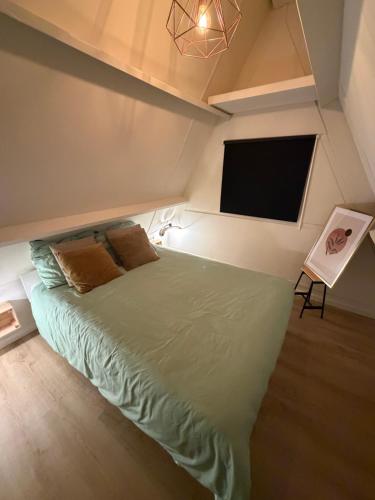 una camera da letto con un letto verde e una TV a schermo piatto di De Lodge a Durbuy