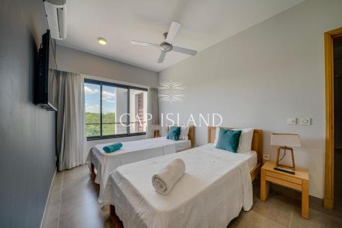 two beds in a room with a window at Penthouse vue piscine lagon, 200m de la plage in Mont Choisy
