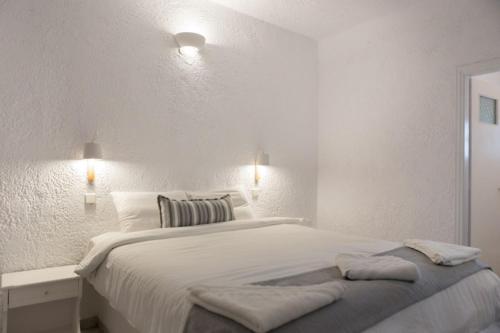 Un dormitorio blanco con una cama grande con dos almohadas. en Artemis Suites, en Megalokori