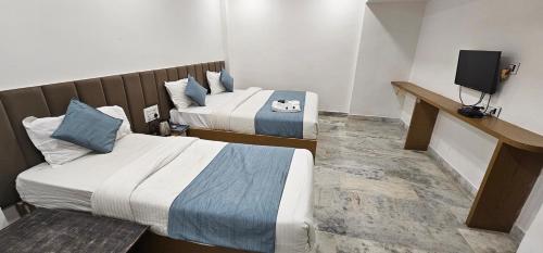 a hotel room with two beds and a television at HOTEL MAHER Inn in Ahmedabad