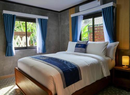 Schlafzimmer mit einem großen Bett und blauen Vorhängen in der Unterkunft Baan Ati Villas in Ban Han Pa To