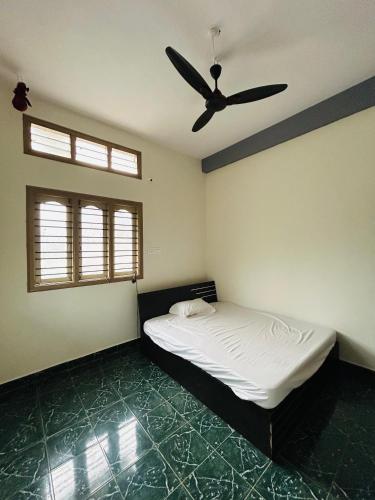 a bedroom with a bed and a ceiling fan at Pritam Homestay in Hubli