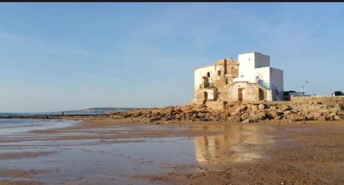 an old building on the shore of a beach at The Bay House Essaouira in Essaouira