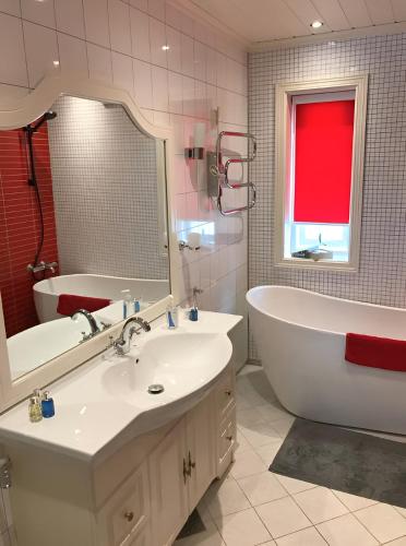 a bathroom with a tub and a sink and a tub and a mirror at Hamsun Panorama med sauna in Åmli
