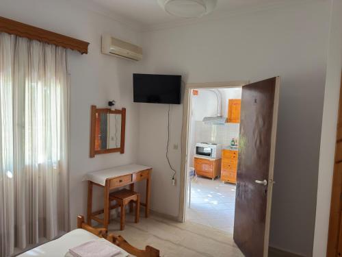 uma sala com um quarto com uma secretária e uma televisão em Helena & Giorgio Rooms Cfu em Agios Georgios