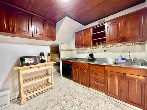Una cocina grande con gabinetes de madera y fregadero. en Navidad en familia 2 hab balcón cerca CC Mayorca, en Sabaneta