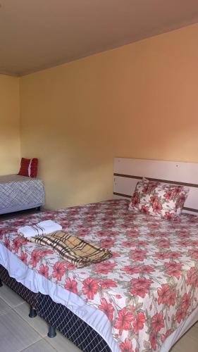 a bedroom with a bed with a floral bedspread at JR POUSADA in Morro do Chapéu