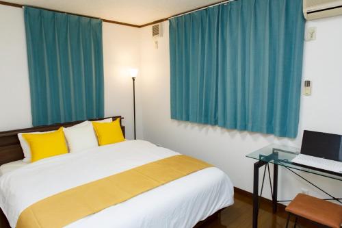 ein Schlafzimmer mit einem Bett und einem Schreibtisch mit einem Laptop in der Unterkunft 一棟貸 風kaze in Ōgaki