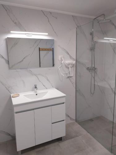 a white bathroom with a sink and a shower at Apartamentos do Lameirinho in Angra do Heroísmo