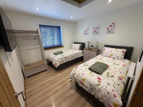 a bedroom with two beds and a window at Woodway Lodge in Dumfries