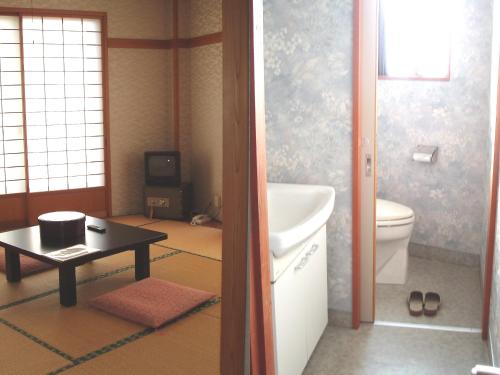 a bathroom with a sink and a toilet and a table at Shinazawa in Nozawa Onsen