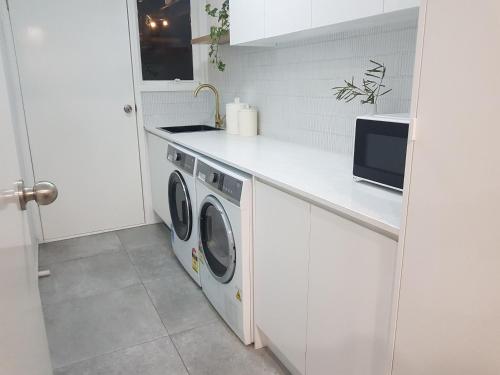 a white kitchen with a washer and dryer at Entire home in Cranbourne West in Cranbourne West