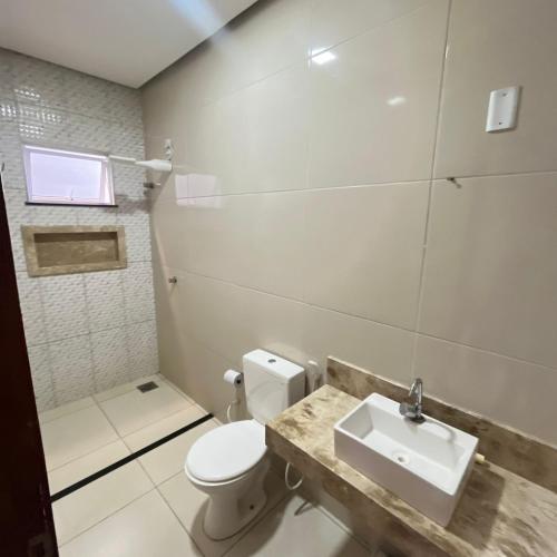 a bathroom with a white toilet and a sink at Casa com 3 dormitórios na Praia do Preá com Piscina in Prea
