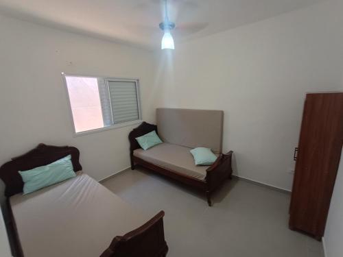 a room with two beds and a couch and a window at Aconchego em Bertioga in Bertioga