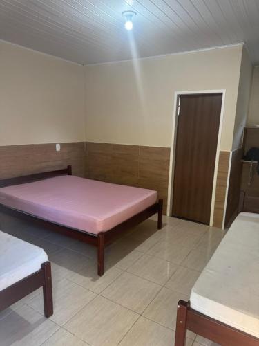 Habitación con cama rosa y puerta en Casa de Praia com Piscina em frente à praia para até 32 pessoas, en Vera Cruz de Itaparica