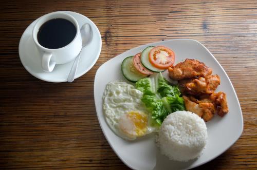a plate of food with eggs broccoli and rice and a cup of coffee at Spaces Hotel Makati in Manila