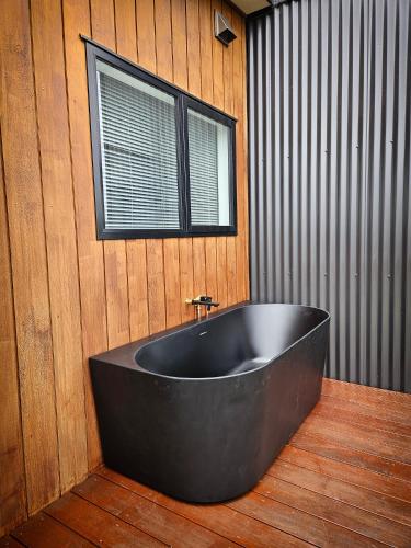a black tub in a room with a window at The Savvy Retreat - vineyard views in Martinborough