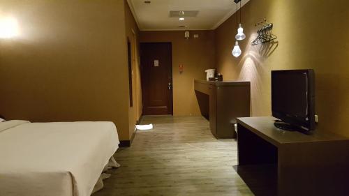 a hotel room with a bed and a tv at The Riverside Hotel & Motel in Kaohsiung