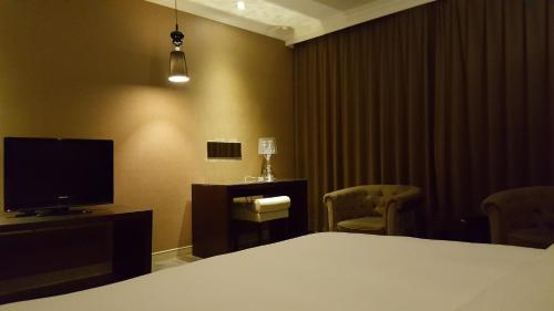 a hotel room with a bed and a television at The Riverside Hotel & Motel in Kaohsiung