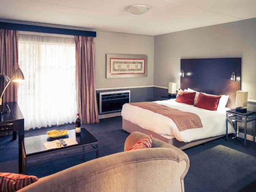 una habitación de hotel con una cama y un sofá en Mercure Hotel Nelspruit, en Nelspruit