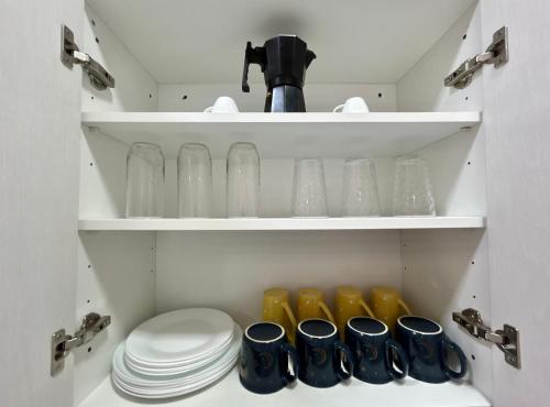 a cupboard with plates and glass dishes in it at Residencial de montaña Los Quetzales in Poás