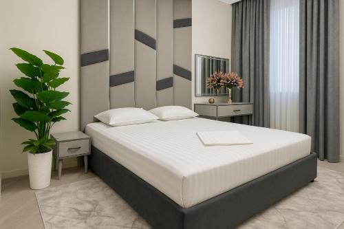 Un dormitorio con una gran cama blanca y una planta en Tashkent Park View Suites - ApartmentHotels uz, en Tashkent