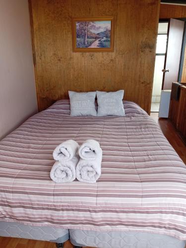 a bed with three rolled up towels on it at Entre lagos Departamento in Puyehue