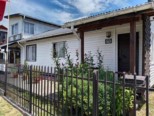 a white house with a fence in front of it at entrre lagos Departamento in Puyehue