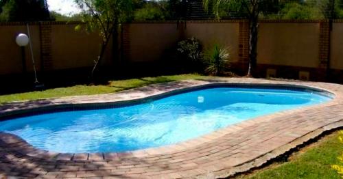 a small swimming pool in a yard with a brick fence at Kloppenheim Sectional Lifestyle Complex in Ellisras