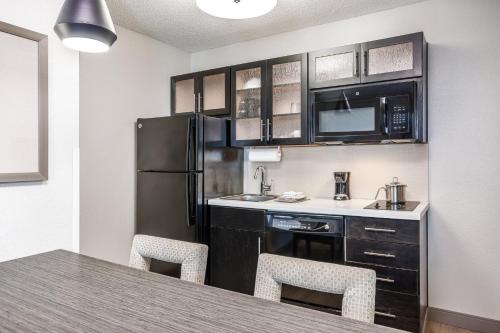 a kitchen with a refrigerator and a table with chairs at Candlewood Suites Indianapolis Northeast by IHG in Indianapolis