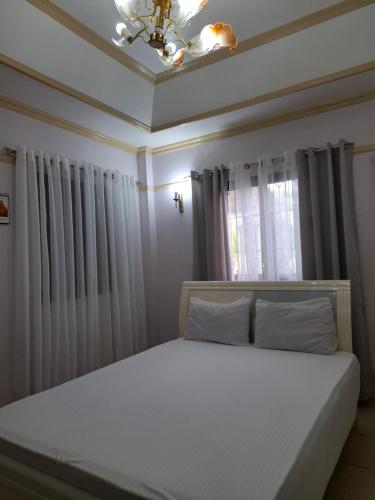 a bedroom with a white bed with a window at Hill View Home Stay Bohol in Panglao