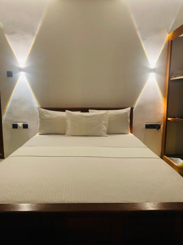 a bedroom with a bed with two lights on it at Glossy Lake View in Hambantota