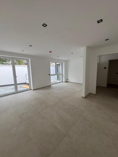 an empty room with white walls and large windows at Genuss Apartment in Purbach am Neusiedlersee