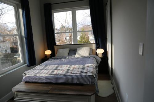 a bedroom with a bed with two windows at Charming Carriage House in NE Washington DC in Washington